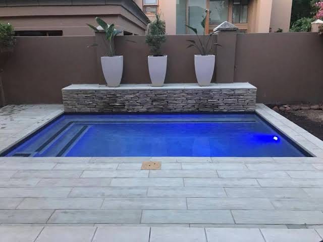 Luxury in-ground pool with blue LED lighting and white planters